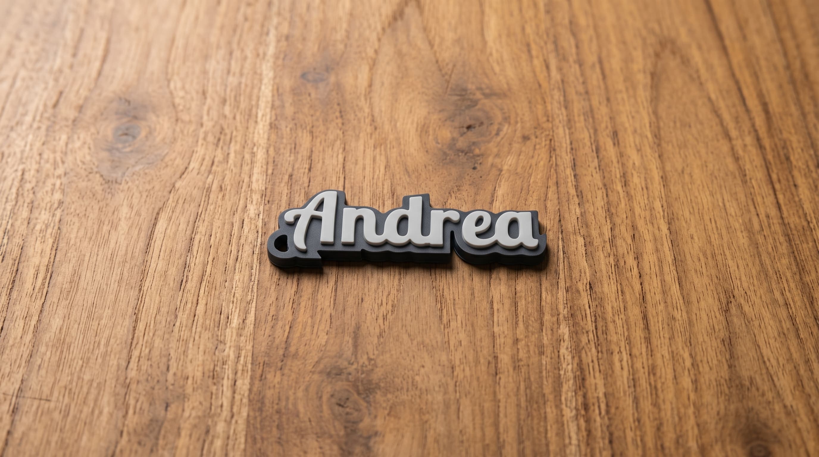 A printed name keychain reading Andrea in white script on a dark base